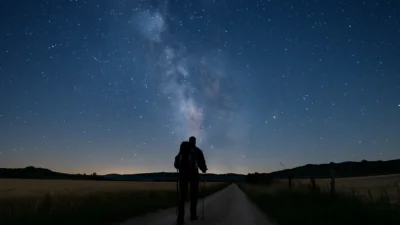 Camiñante solitario nun sendeiro do Camiño baixo o ceo estrelado